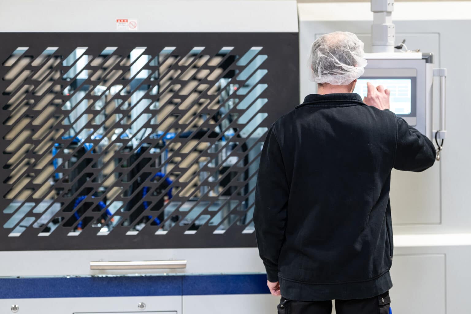 Opérateur supervisant une machine industrielle de transformation d’emballages alimentaires.