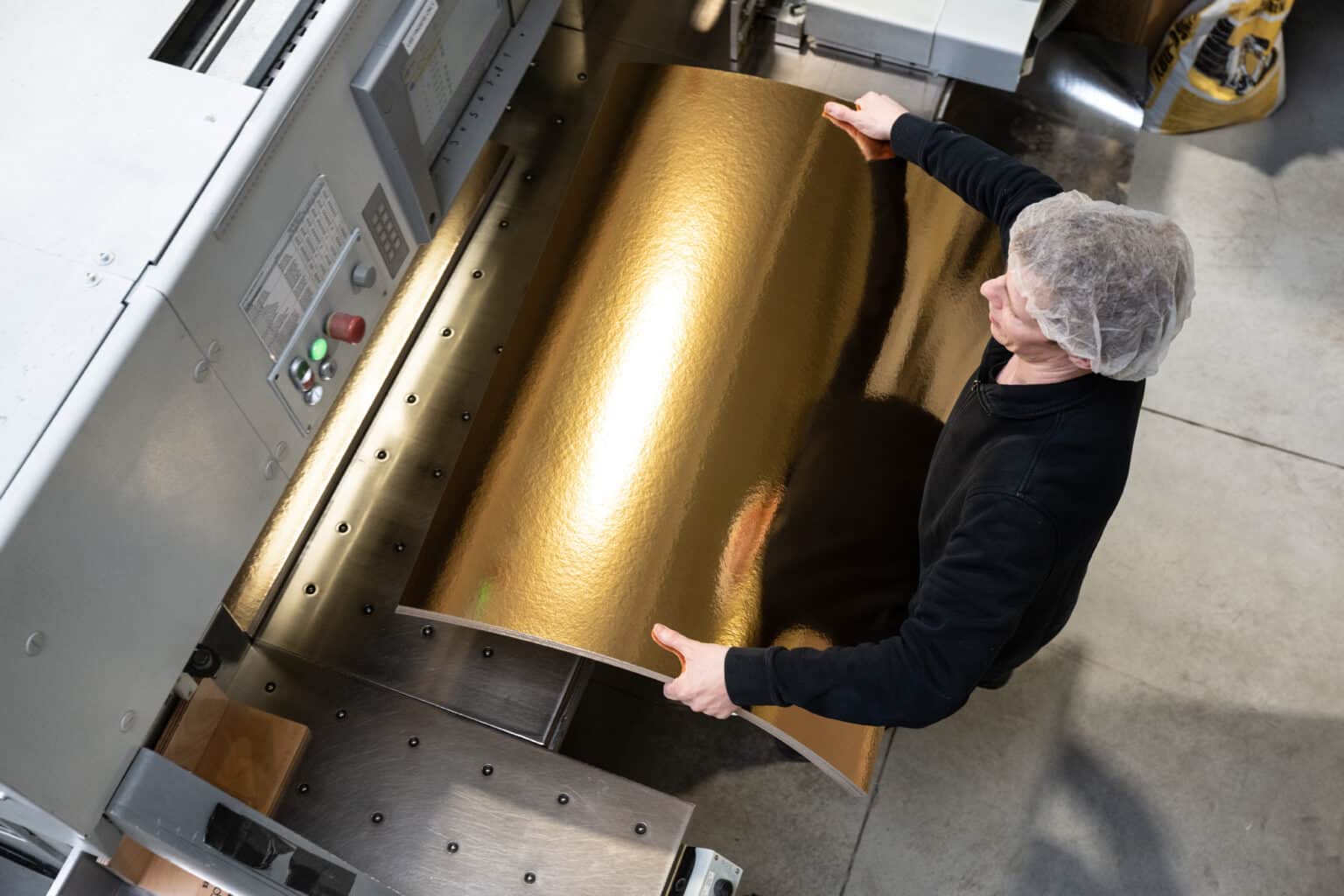 Découpe de plaques cartonnées dorées sur machine industrielle chez Pack ’n Food Solutions.